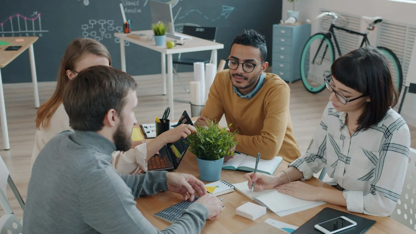 Projektteam plant am Tisch mit Laptop und Notizen